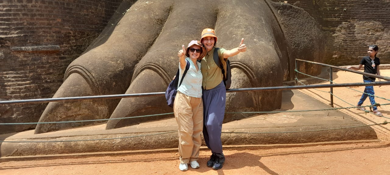 Zwei Gäste neben der riesigen steinernen Löwenpranke am Fuß des Sigiriya-Felsens